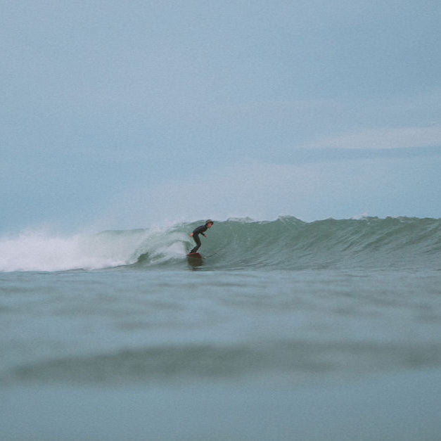 Person surfing a wave in the ocean with a clear sky