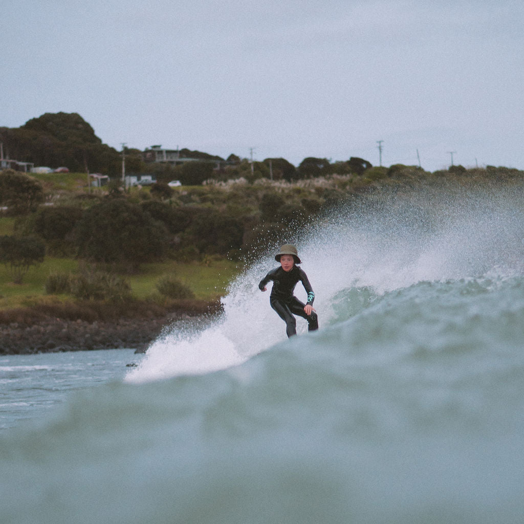 Person surfing on a wave with a coastal landscape in the background